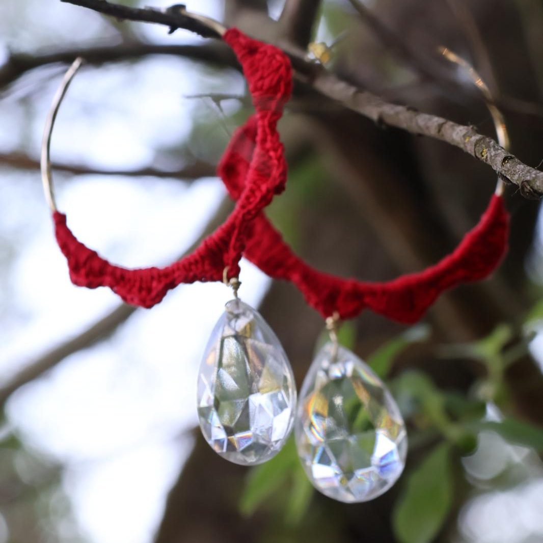 Red lace hoop earrings with large crystal teardrop pendants.